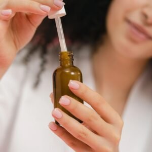 woman using a dropper bottle, focusing on skincare and beauty routine