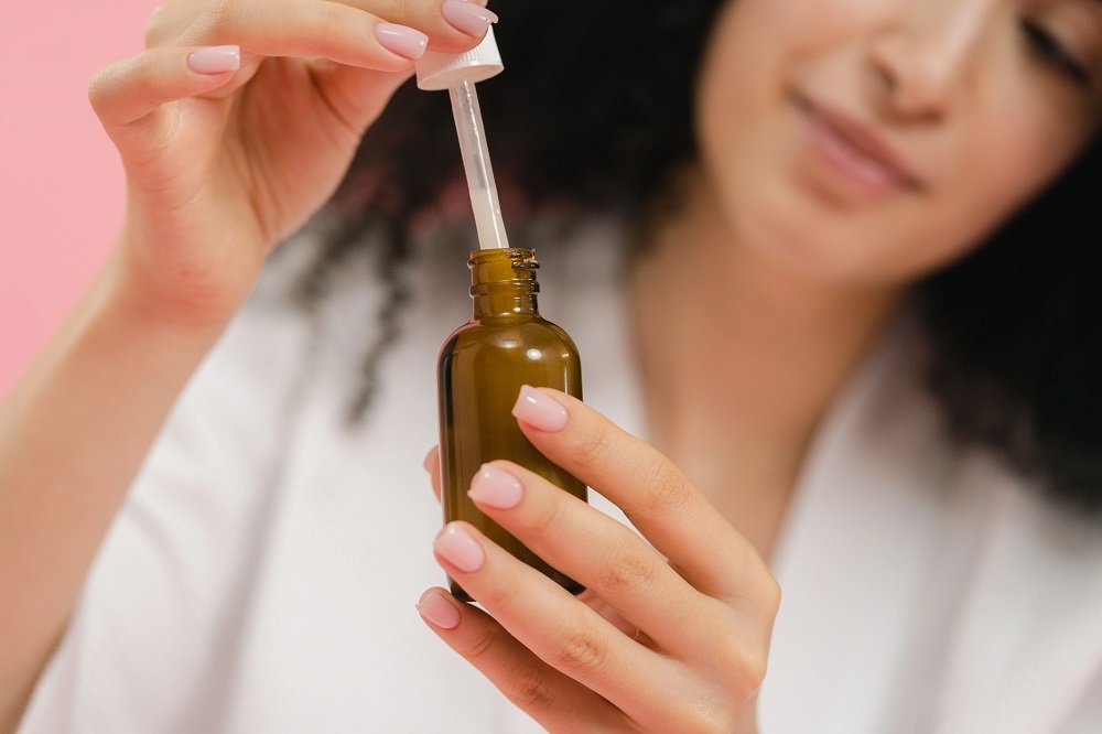 woman using a dropper bottle, focusing on skincare and beauty routine